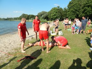 Ratownicy stojący nad osoba wyciągniętą z wody.