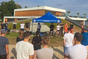 uczestnicy stoją przed policyjnym namiotem i słuchają organizatora