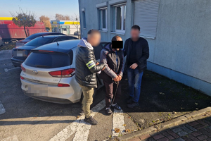 policjanci prowadzą zatrzymanego skutego kajdankami zespolonymi