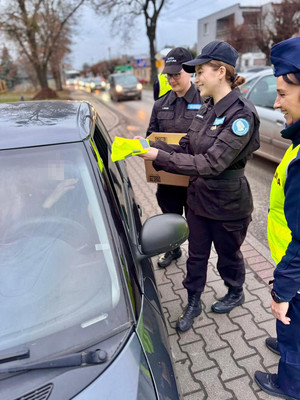 policjanci i uczniowie rozdają odblaski